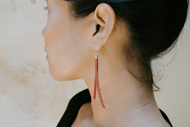 Closeup of woman’s ear with long earring, showing natural contour often achieved with otoplasty surgery.