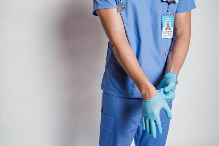 Medical professional in blue scrubs putting on gloves, symbolizing confidentiality and ethical standards in cosmetic surgery.