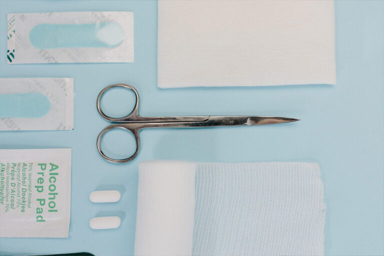 Flat lay of medical tools, gauze, alcohol pads, and scissors representing preparation for cosmetic or plastic surgery.