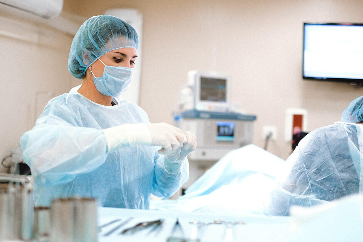 Surgeon in scrubs preparing instruments in an operating room, representing both cosmetic and reconstructive surgical procedures.