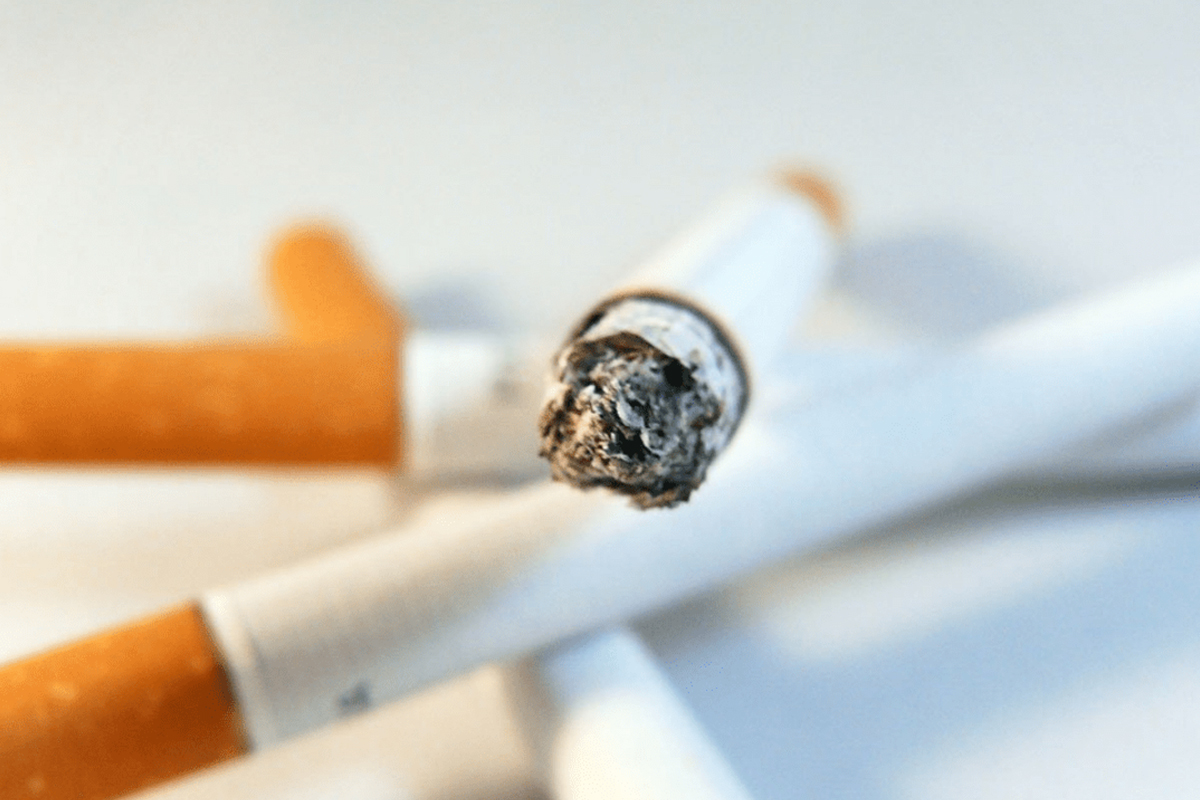 Close-up of a burned cigarette tip, highlighting the importance of quitting smoking before undergoing plastic surgery.