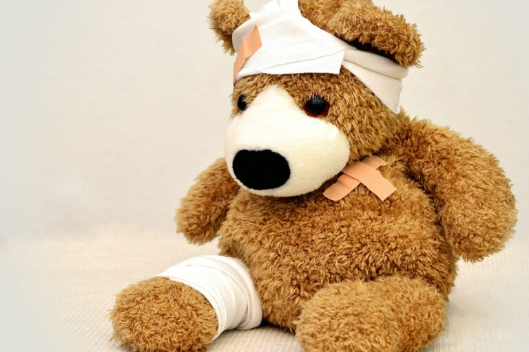 Teddy bear with bandages on head, chest, and leg symbolizing post-surgical wound care and recovery