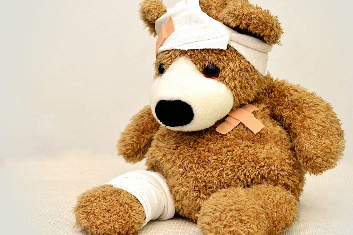 Teddy bear with bandages on head, chest, and leg symbolizing post-surgical wound care and recovery