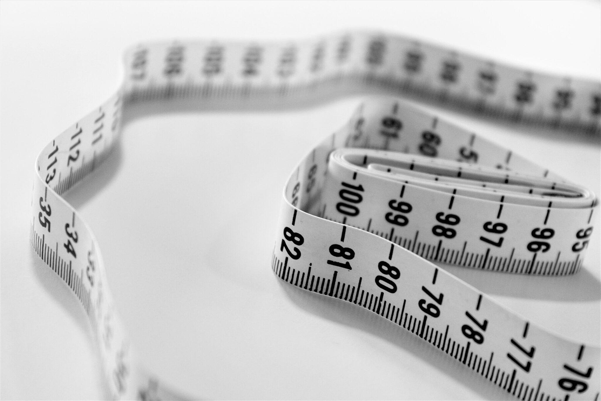 Close-up of a coiled measuring tape, symbolizing body measurement and reshaping through contouring procedures