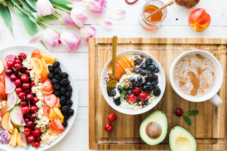 Colorful display of fresh fruits, yogurt bowl, and tea on a wooden board, symbolizing healthy habits before cosmetic surgery