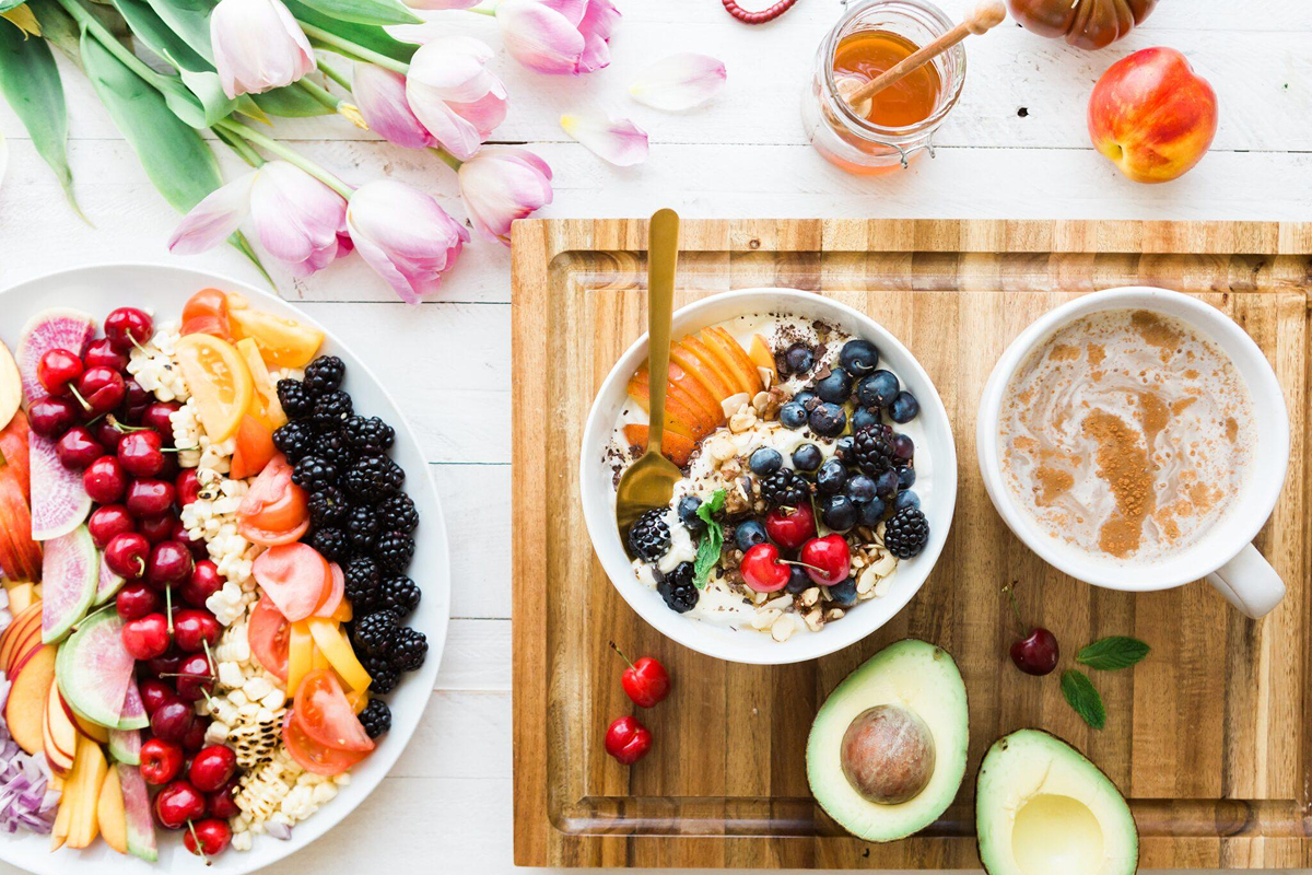 Colorful display of fresh fruits, yogurt bowl, and tea on a wooden board, symbolizing healthy habits before cosmetic surgery