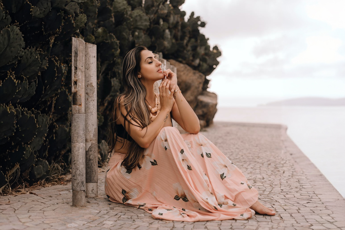 Woman sitting peacefully by the water in a long dress, representing confidence after double chin treatment