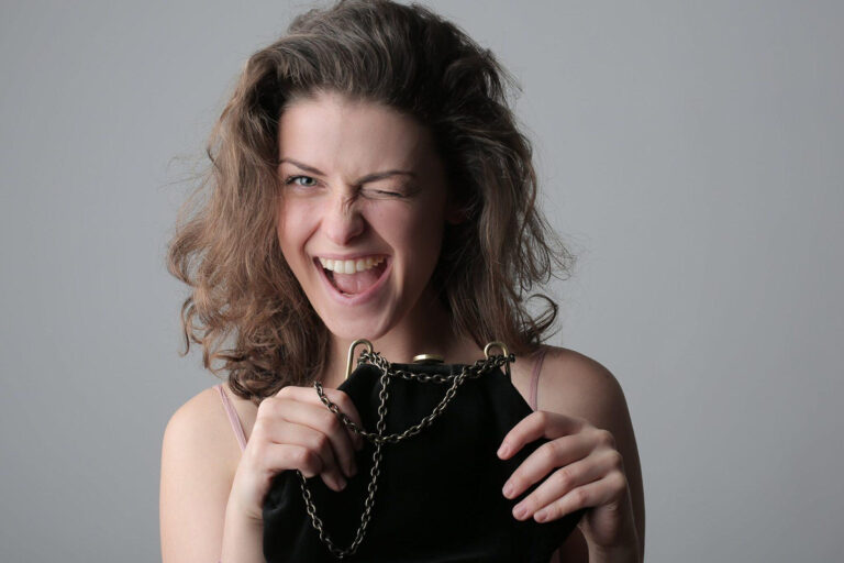 Woman smiling and winking while holding a black purse, representing youthful expression and skin care.