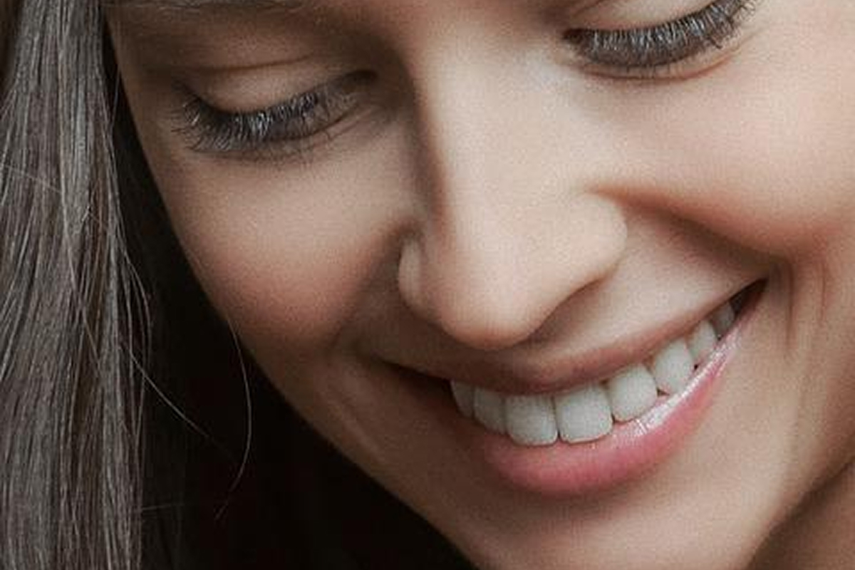 Close-up of a smiling woman’s face showing a smooth nose contour, representing the subtle, natural-looking results of non-surgical rhinoplasty