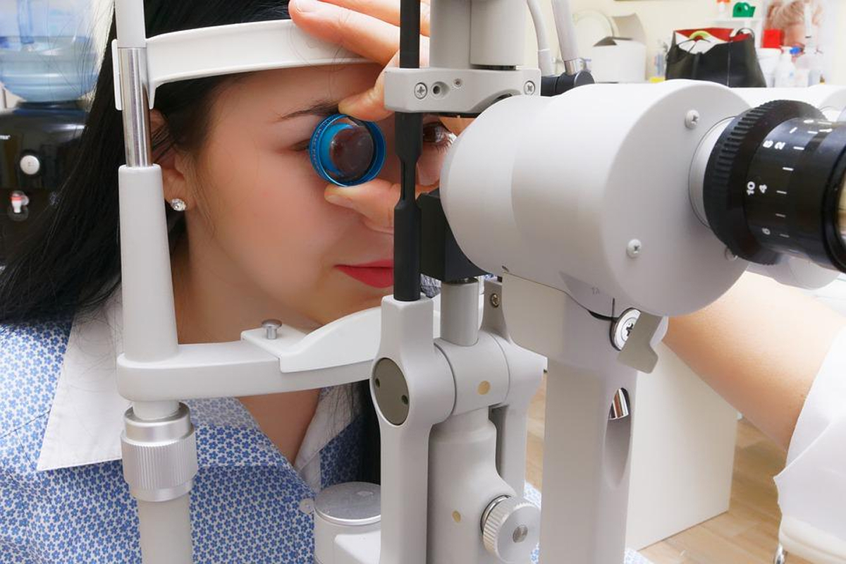 Woman undergoing an eye exam with specialized equipment, representing an ophthalmologist evaluating vision for LASIK surgery