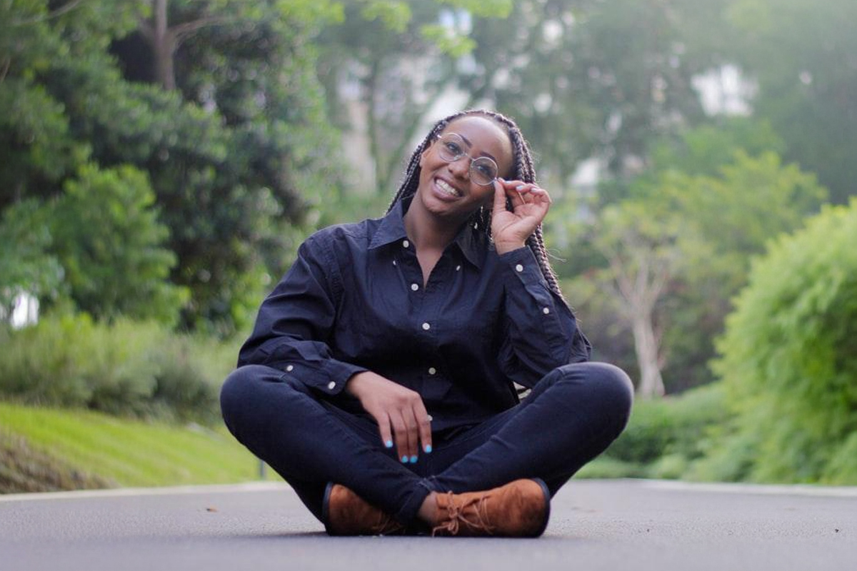 Smiling woman sitting cross-legged outdoors adjusting her glasses, representing consideration of LASIK vision correction candidacy