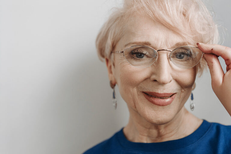 Smiling older woman wearing glasses, symbolizing healthy aging and early detection to delay cataract development