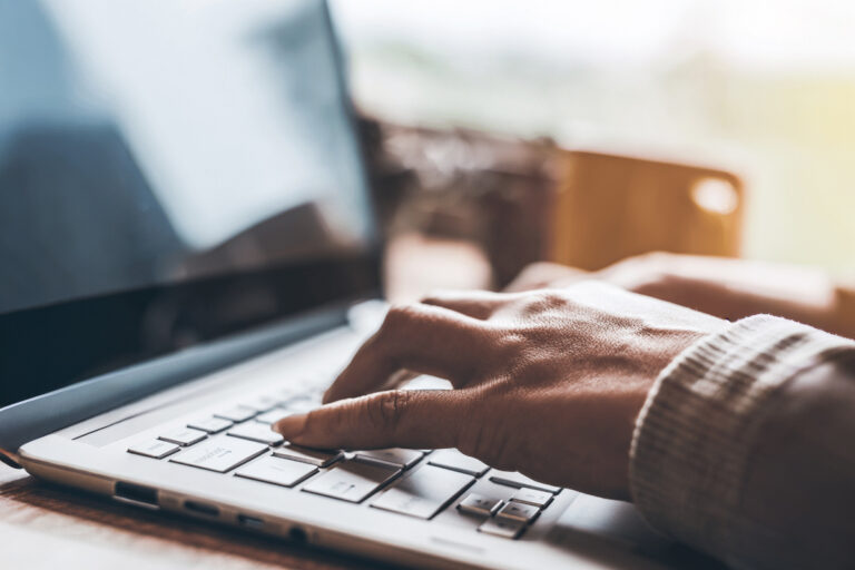 Close-up of hand typing on laptop keyboard, representing the process of researching qualified LASIK surgeons online