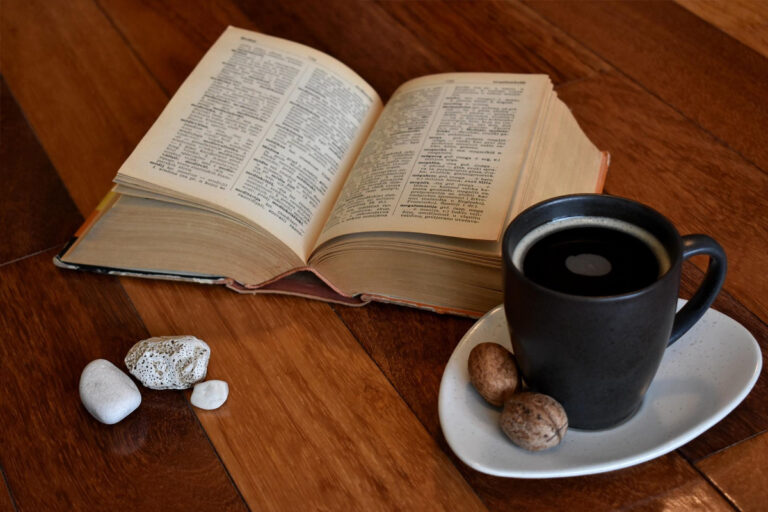 Open dictionary next to a black coffee mug and walnuts on wood surface, symbolizing defining and learning about Botox