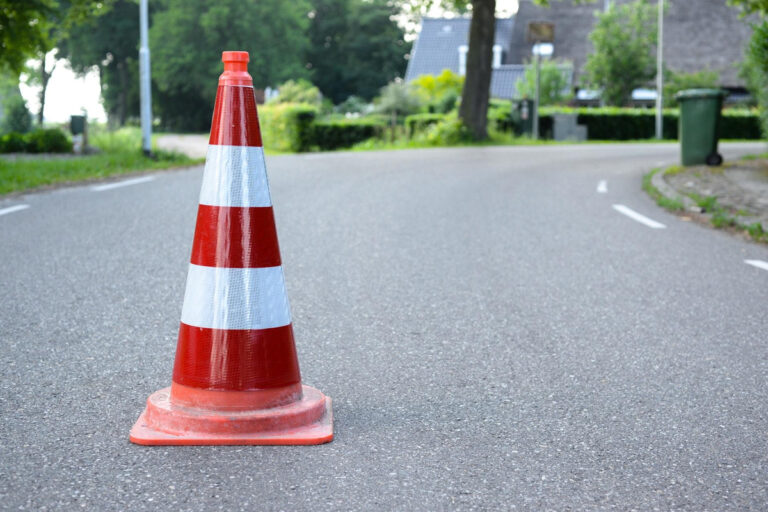 Orange and white traffic cone on empty road symbolizing caution and pre-surgery restrictions before rhinoplasty procedure.