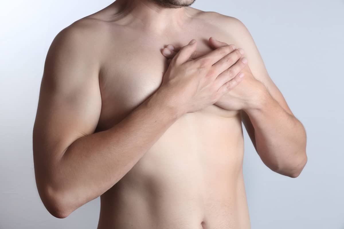 A shirtless man rests his hands on his chest, illustrating the physical symptoms of gynecomastia potentially caused by a thyroid imbalance.